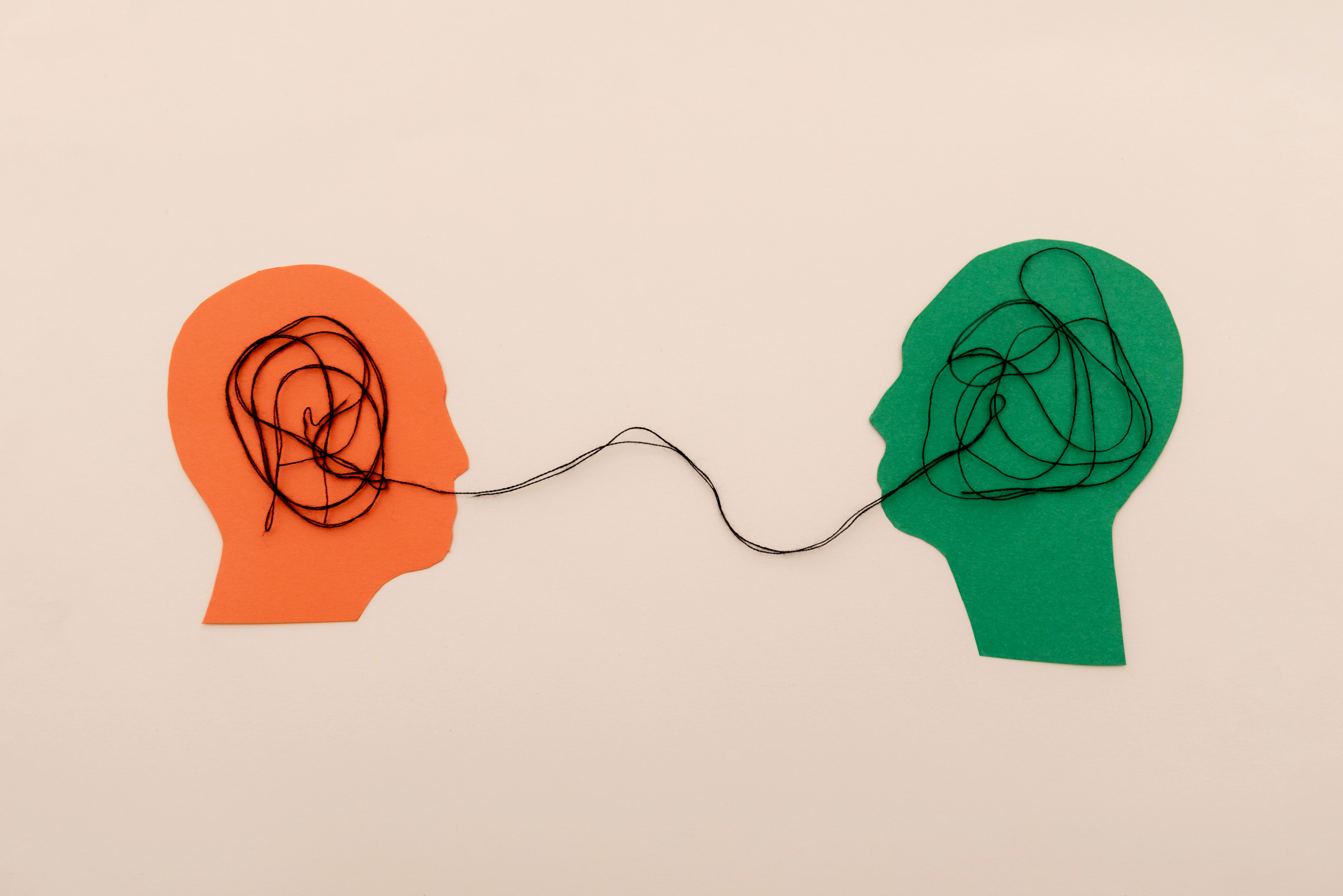 Two human head silhouettes Connected by tangled Thread, Symbolizing Communication and Understanding