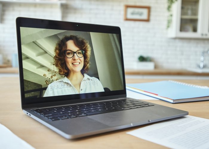 Close up of laptop screen with attractive female teacher smiling during video call, having online lesson with students studying from home. Technology, distance learning concept
