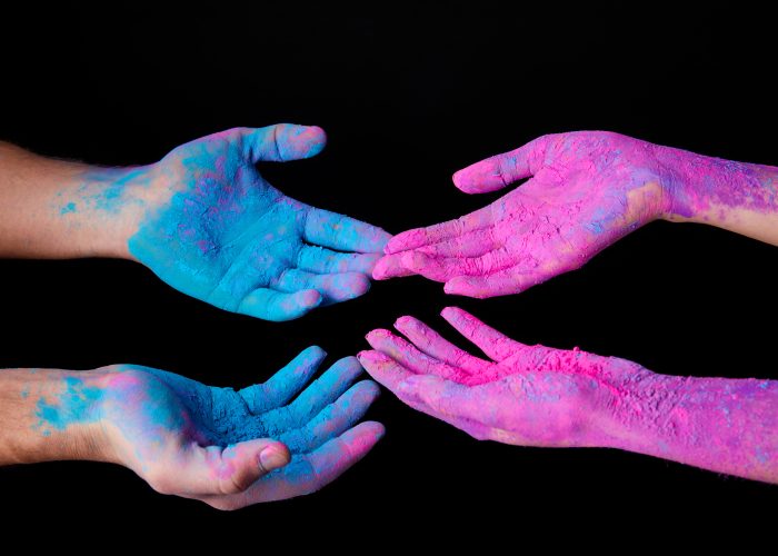 cropped view of couple with pink and blue holi paint on hands, isolated on black